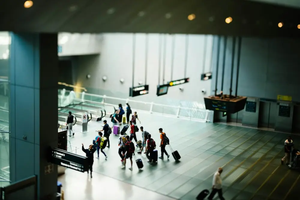 A group of travelers with luggage walking through a modern airport terminal, illustrating coordinating distributed workforce